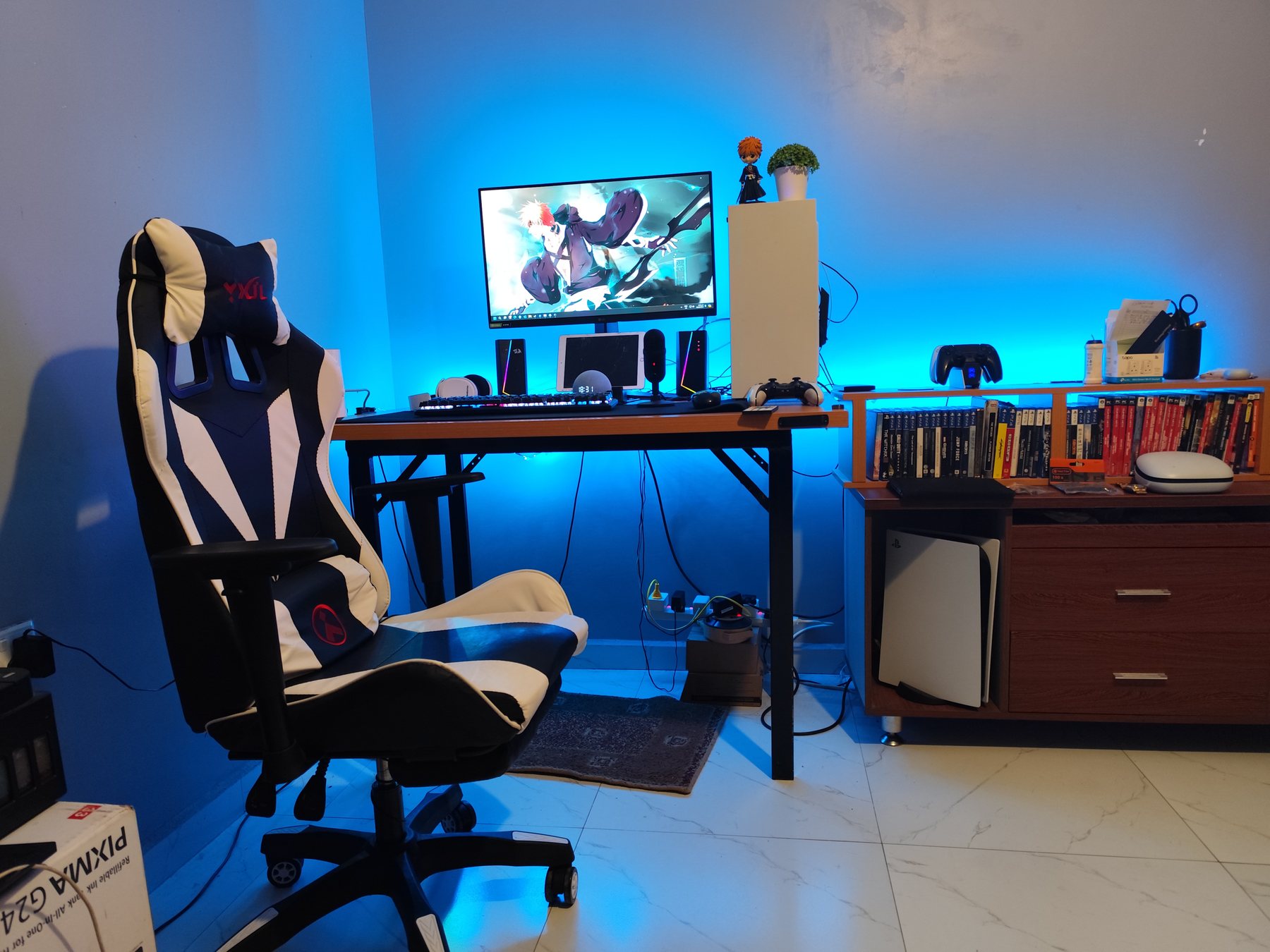 Blue-lit gaming setup with chair, monitor and console area